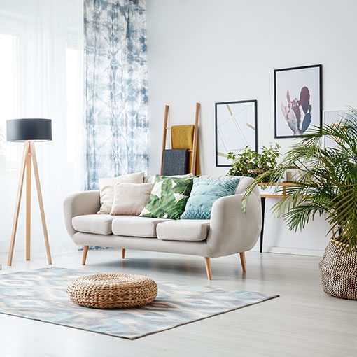 A living room with a white couch, a plant, and a lamp